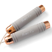 Two gray jump ropes with rose gold ends on a white background, branded 'Brazilian Booty Co'.
